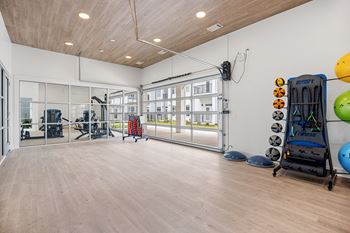 a fitness room with weights and cardio equipment and a glass windowat Oak Grove at Blake Farm, Wilmington, NC, 28411